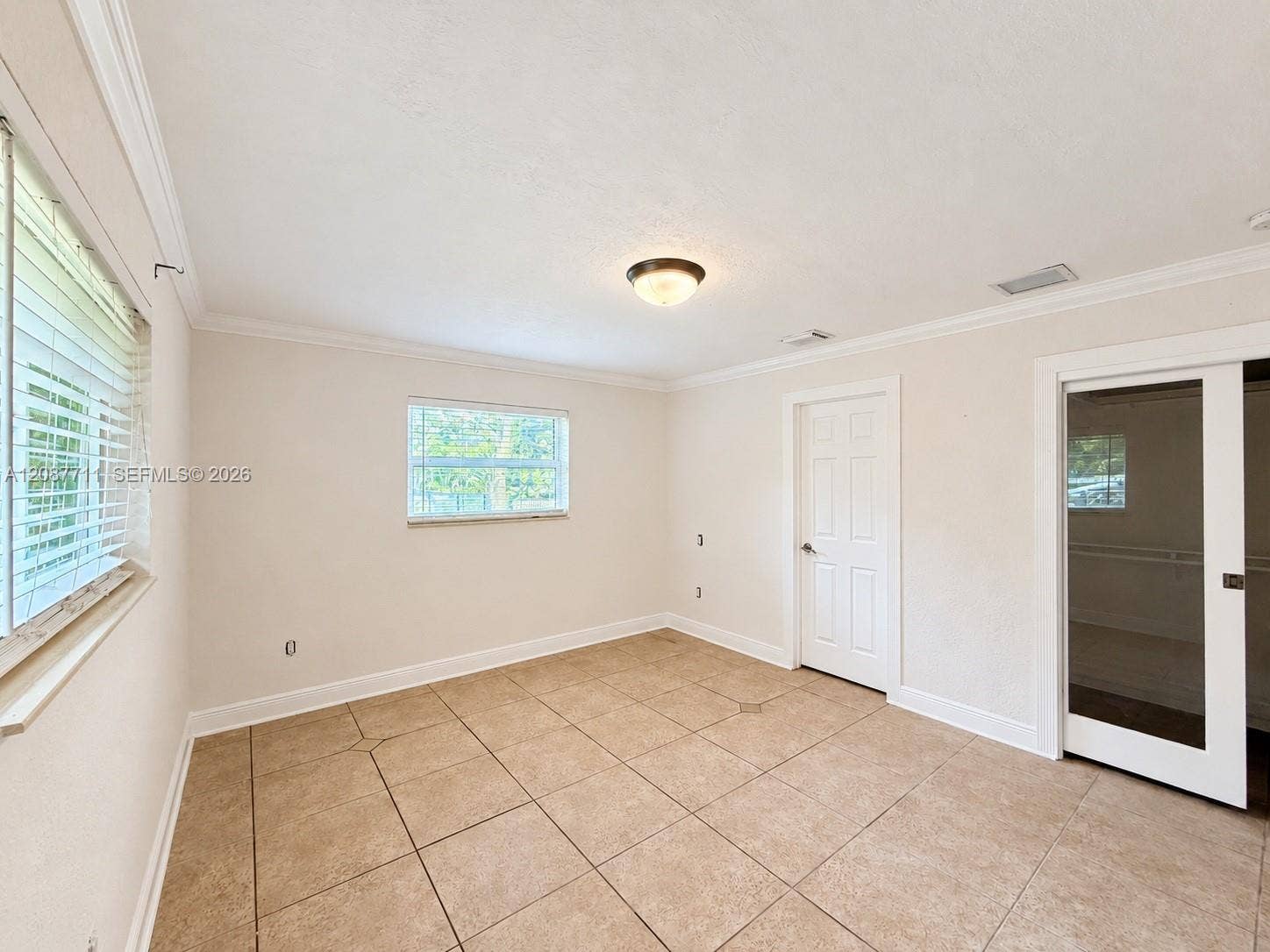 80 NE 162nd Street, Miami, Miami, FL 33162 Neutral-toned interior space featuring tile flooring, crown molding, multi-pane windows, and a sliding glass panel door