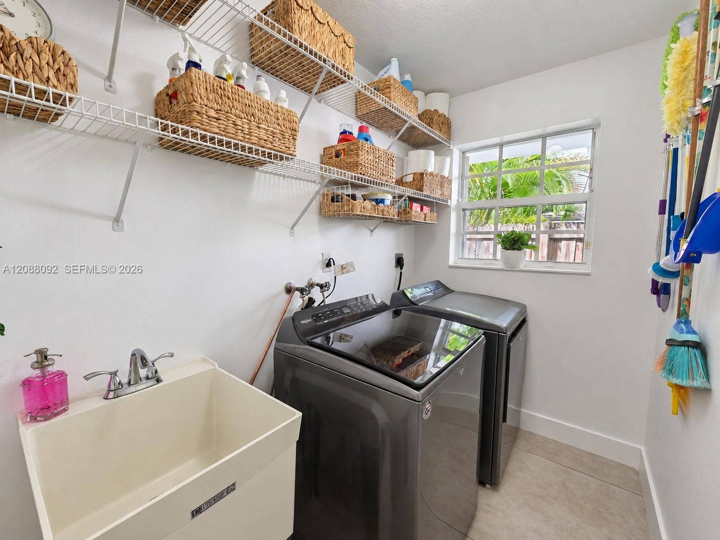 Spacious Laundry room with utility tub, sheves for storage, washer and dryer with lots of natural light.