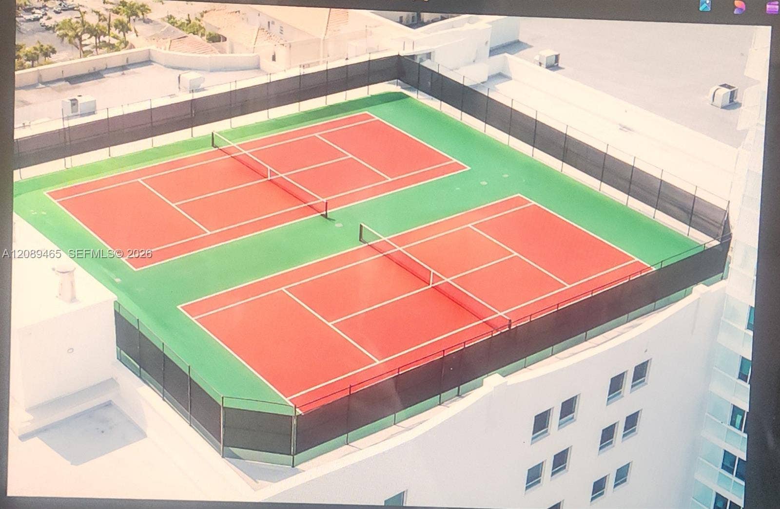 1745 E Hallandale Beach Boulevard, #2308W, Hallandale Beach, FL 33009 Rooftop amenity featuring two full-size tennis courts with red colored playing surfaces and green surrounds, enclosed by a perimeter fence