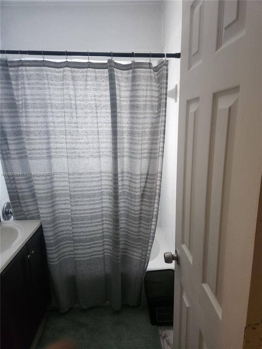 Bathroom featuring a vanity with a light-colored countertop and dark cabinetry, a shower-tub combination, and a six-panel interior door