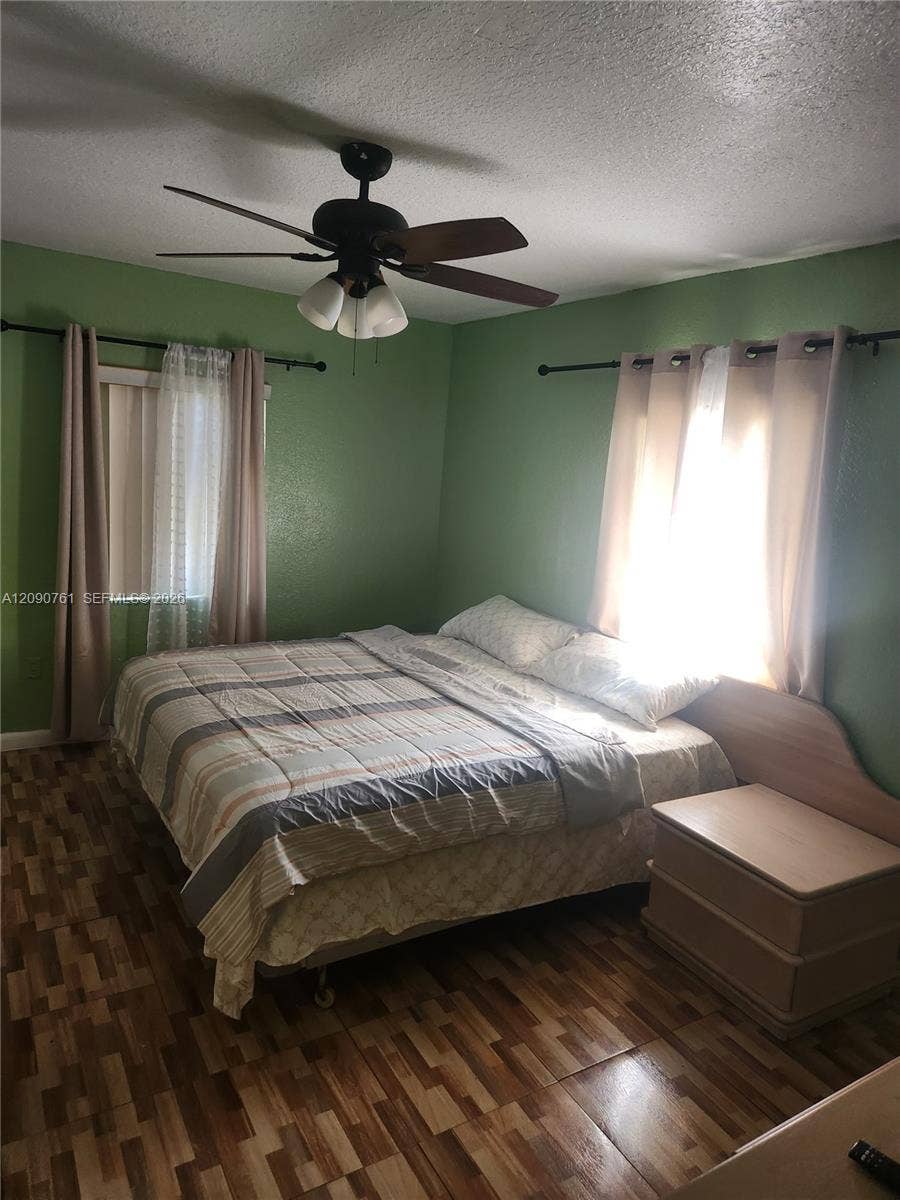 Wood-finish flooring, dual windows, and a central ceiling fan with integrated lighting