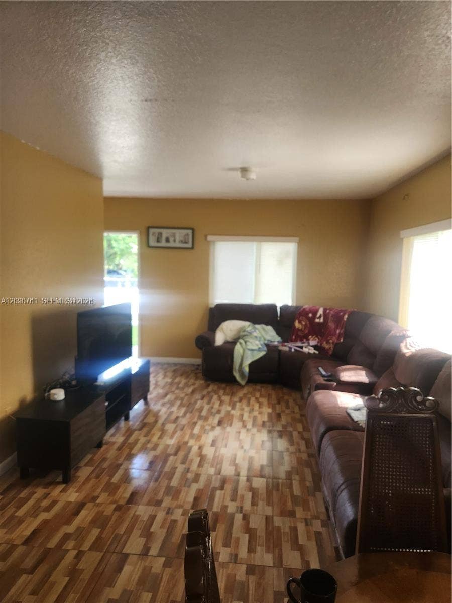 Living area featuring patterned tile flooring and dual windows with horizontal blinds