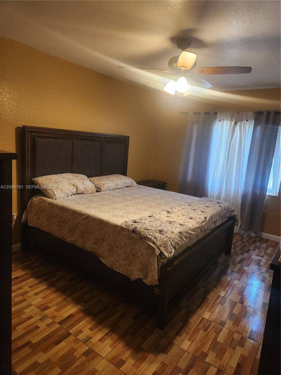 Multi-tone tile flooring and a ceiling-mounted light fixture with a three-blade fan