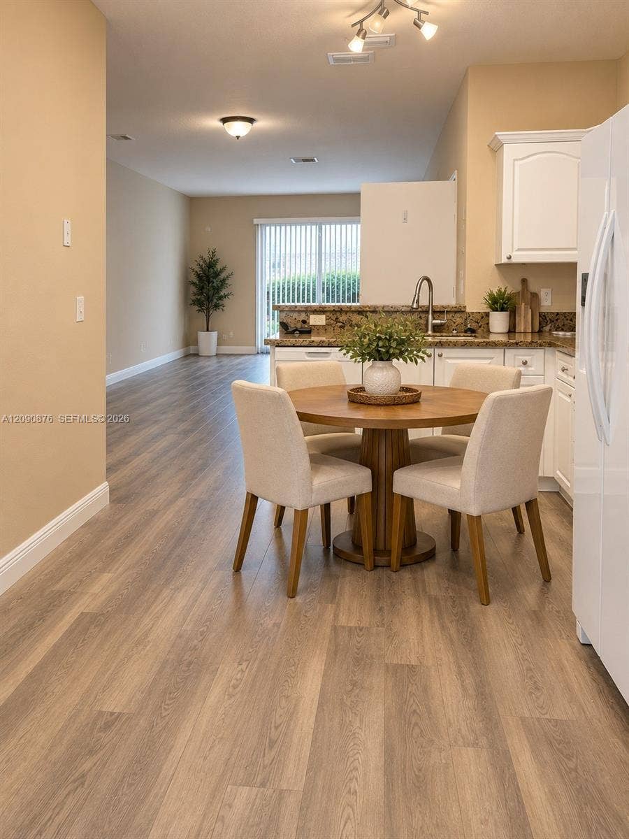 2196 Ensenada Terrace, Weston, FL 33327 Hard-surface wood-finish flooring throughout, track lighting, ceiling-mounted light fixture, white cabinetry, and a sliding glass door