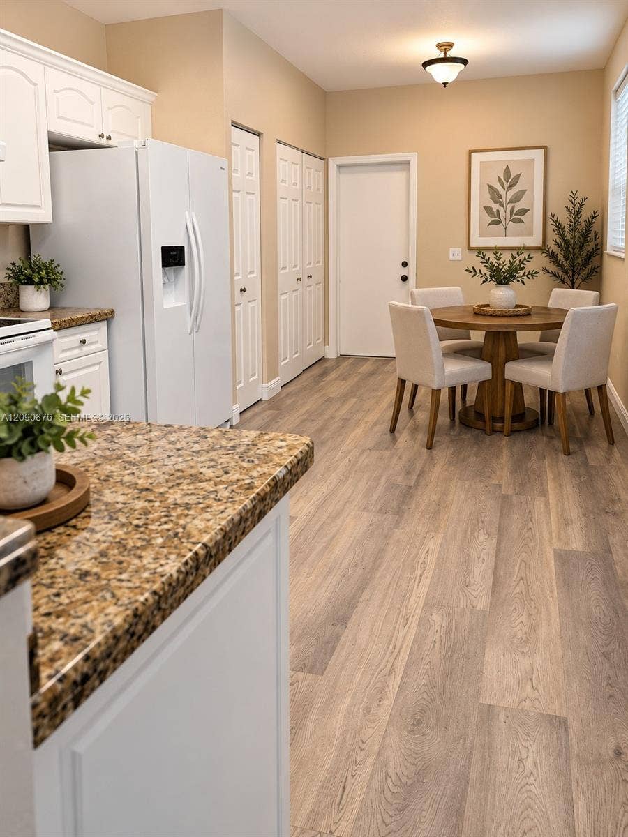 2196 Ensenada Terrace, Weston, FL 33327 Kitchen featuring white cabinetry, granite countertops, wood-finish flooring, and a dining area with a flush-mount light fixture
