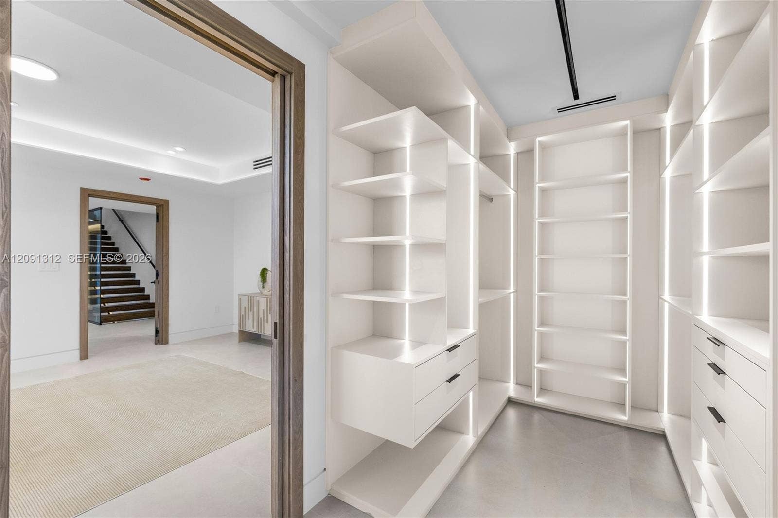 Custom walk-in closet featuring floor-to-ceiling built-in shelving, integrated vertical LED lighting, and drawer storage with matte black hardware
