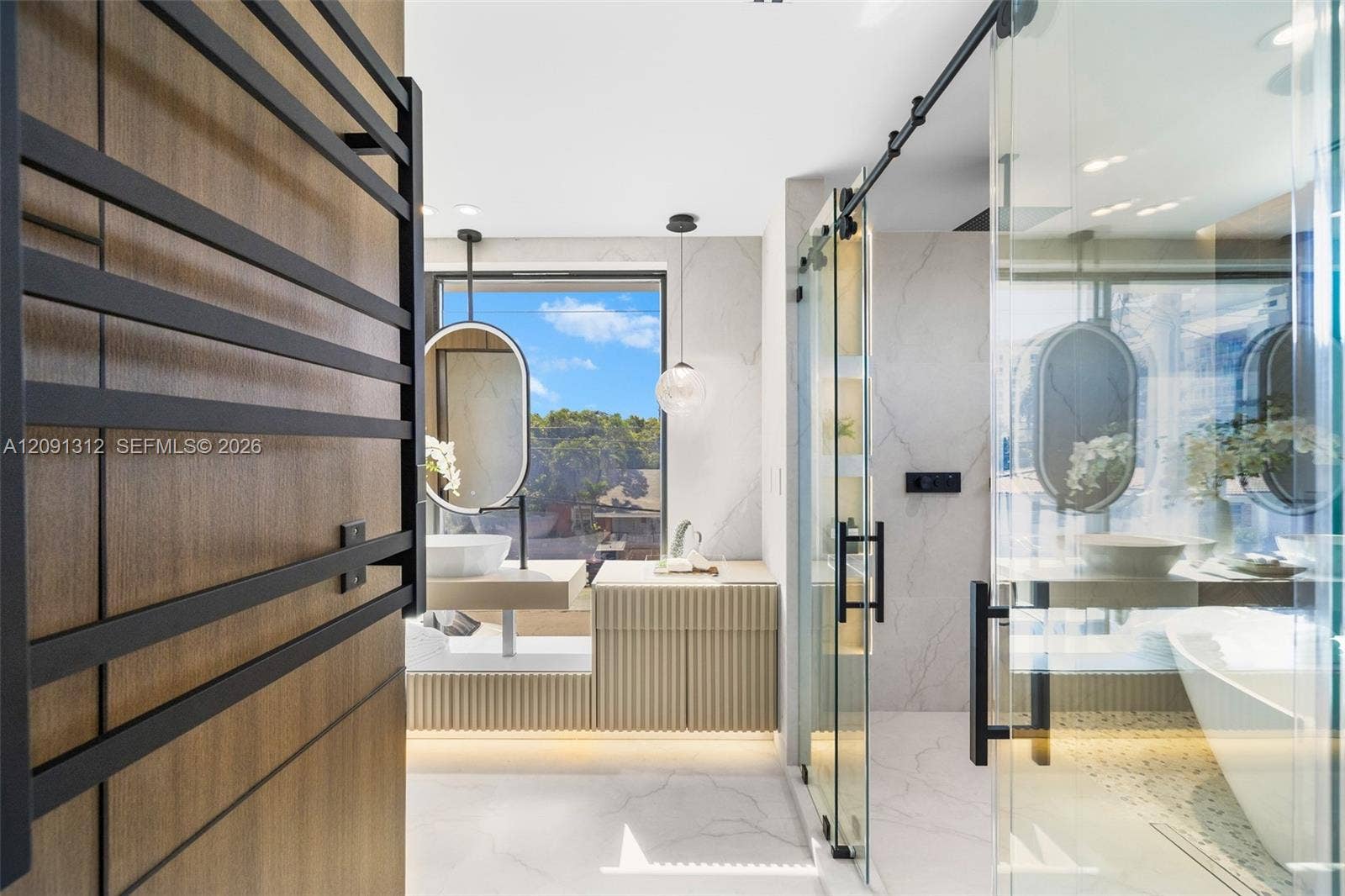 Custom bathroom featuring a large walk-in glass shower with sliding door, floating vanity with vessel sink, matte black hardware, wall-mounted towel warmer, and floor-to-ceiling stone-finish wall tile