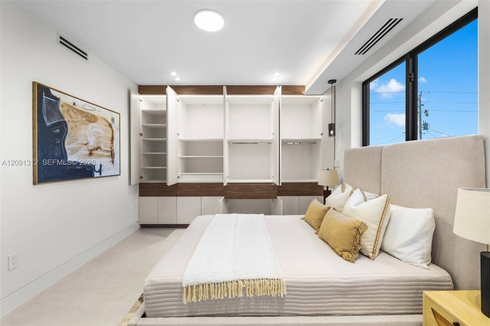 Built-in storage wall with two-tone cabinetry, recessed LED lighting, and large window with black frames