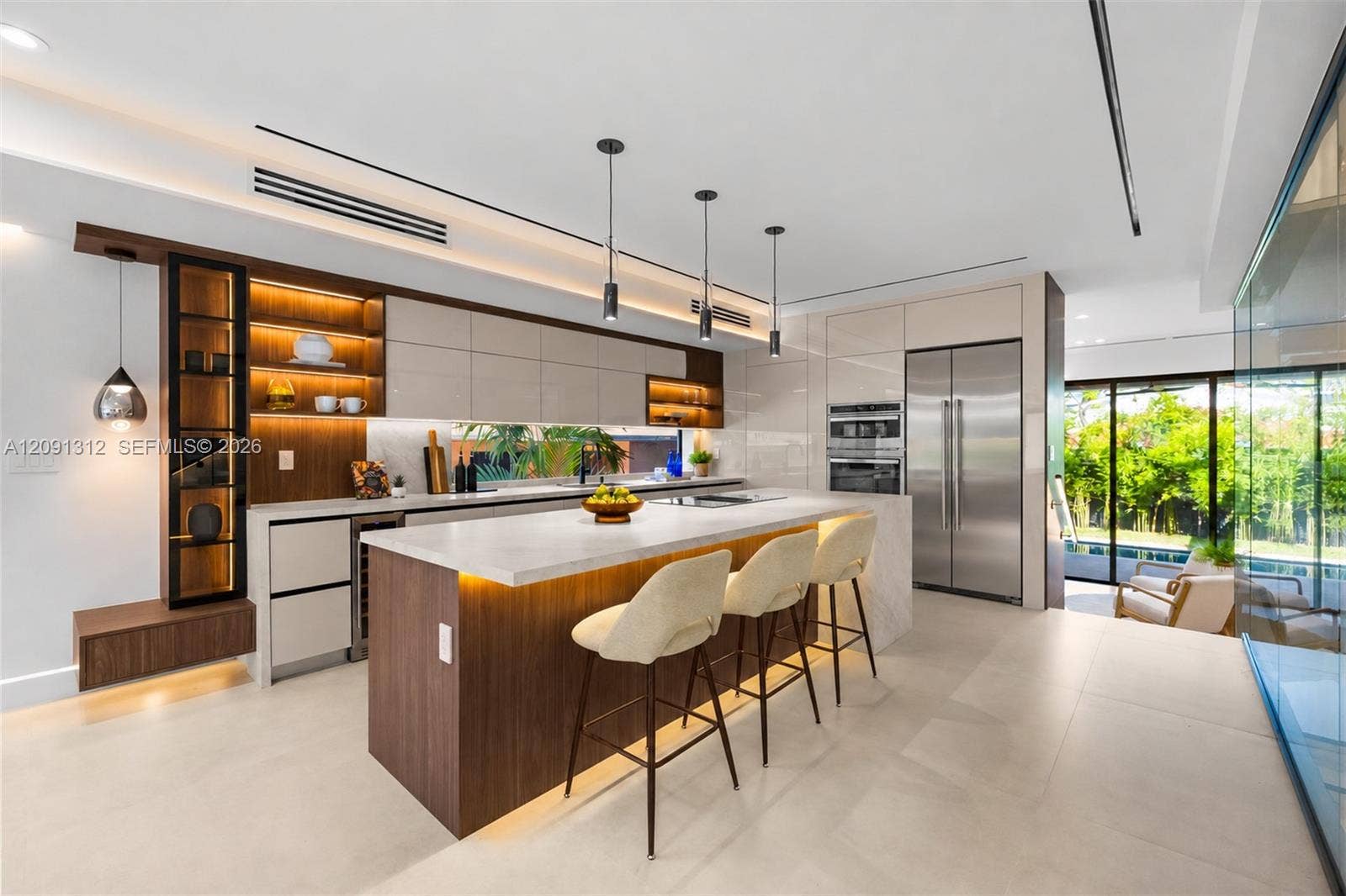 Modern kitchen featuring high-gloss cabinetry, stone-finish countertops, wood-finish island with integrated base lighting, stainless steel appliances, and minimalist pendant lighting