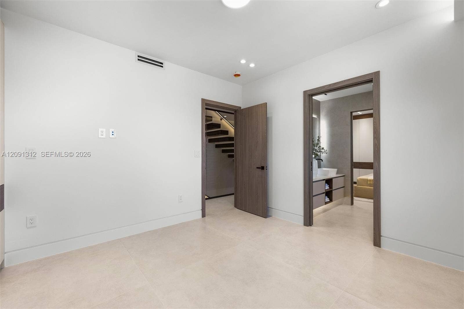 Interior space featuring neutral large-format tile flooring, recessed ceiling lighting, and wood-finish door frames