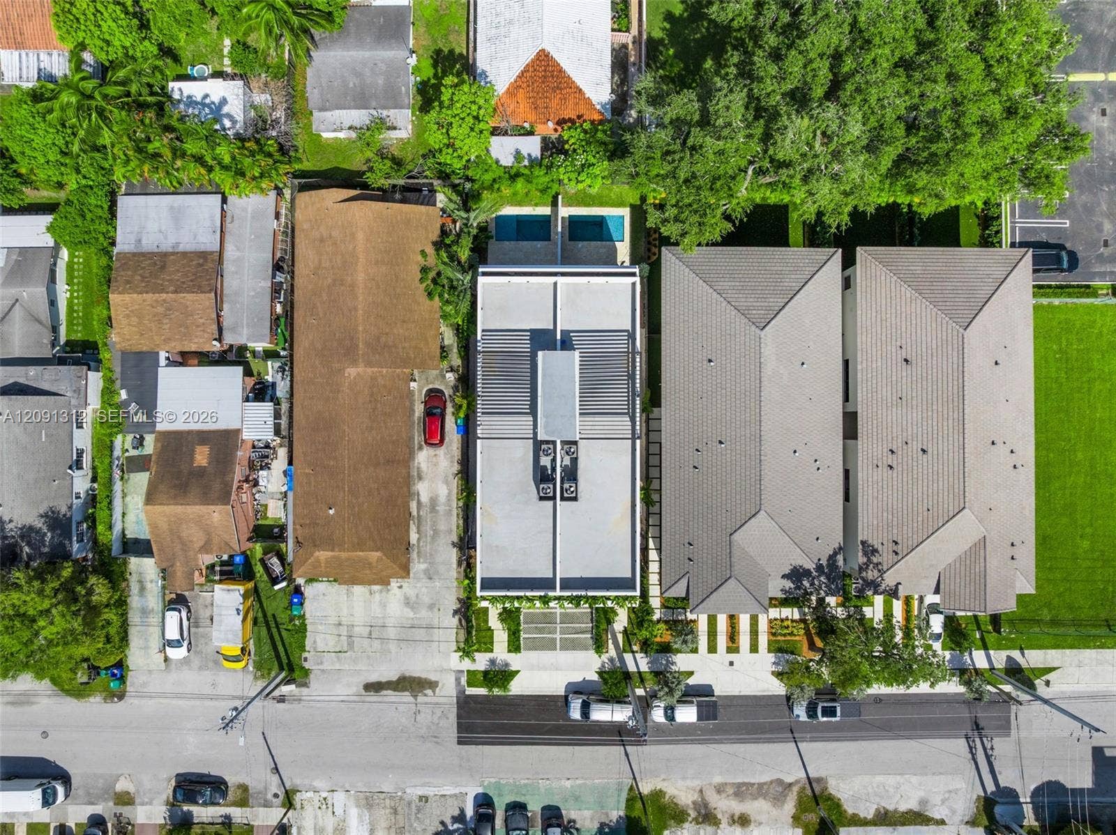 Aerial perspective of a modern property featuring a flat roofline, integrated rooftop mechanical systems, a private swimming pool, and concrete paver hardscaping