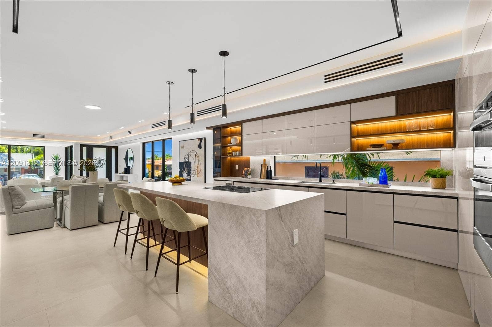 Kitchen featuring a stone-topped waterfall island, flat-panel cabinetry, a horizontal window backsplash, integrated under-cabinet lighting, and porcelain tile flooring