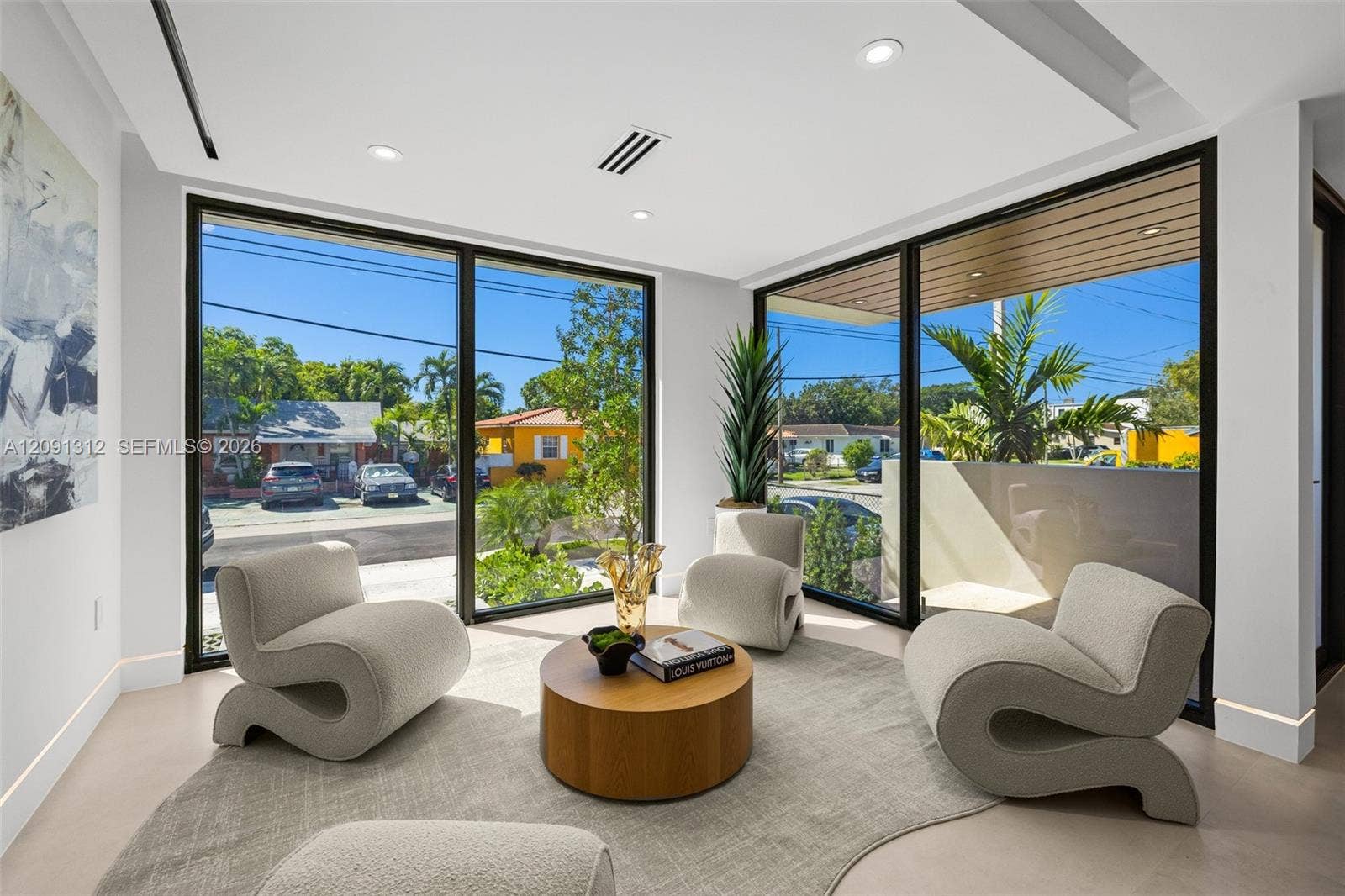 Floor-to-ceiling windows with black frames, recessed ceiling lighting, smooth finish flooring, and a tray ceiling detail