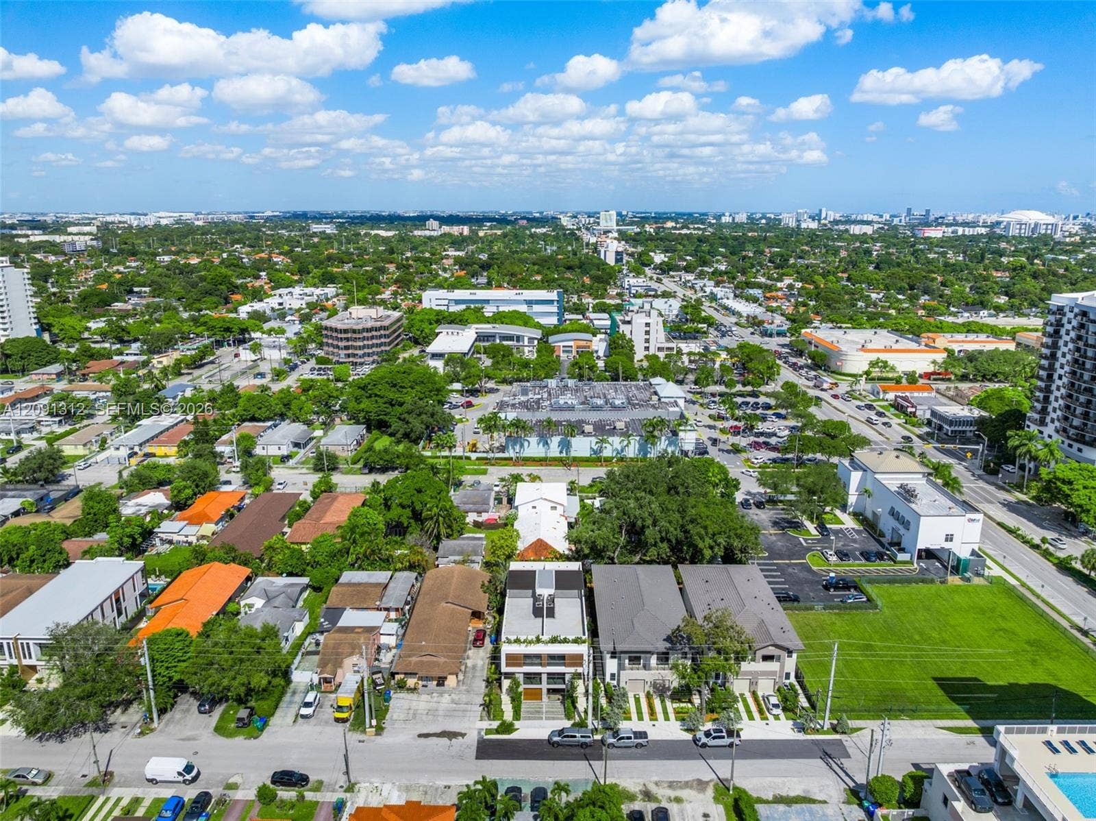 Aerial perspective of a multi-story residence featuring a flat roofline, horizontal facade detailing, and a paved private driveway