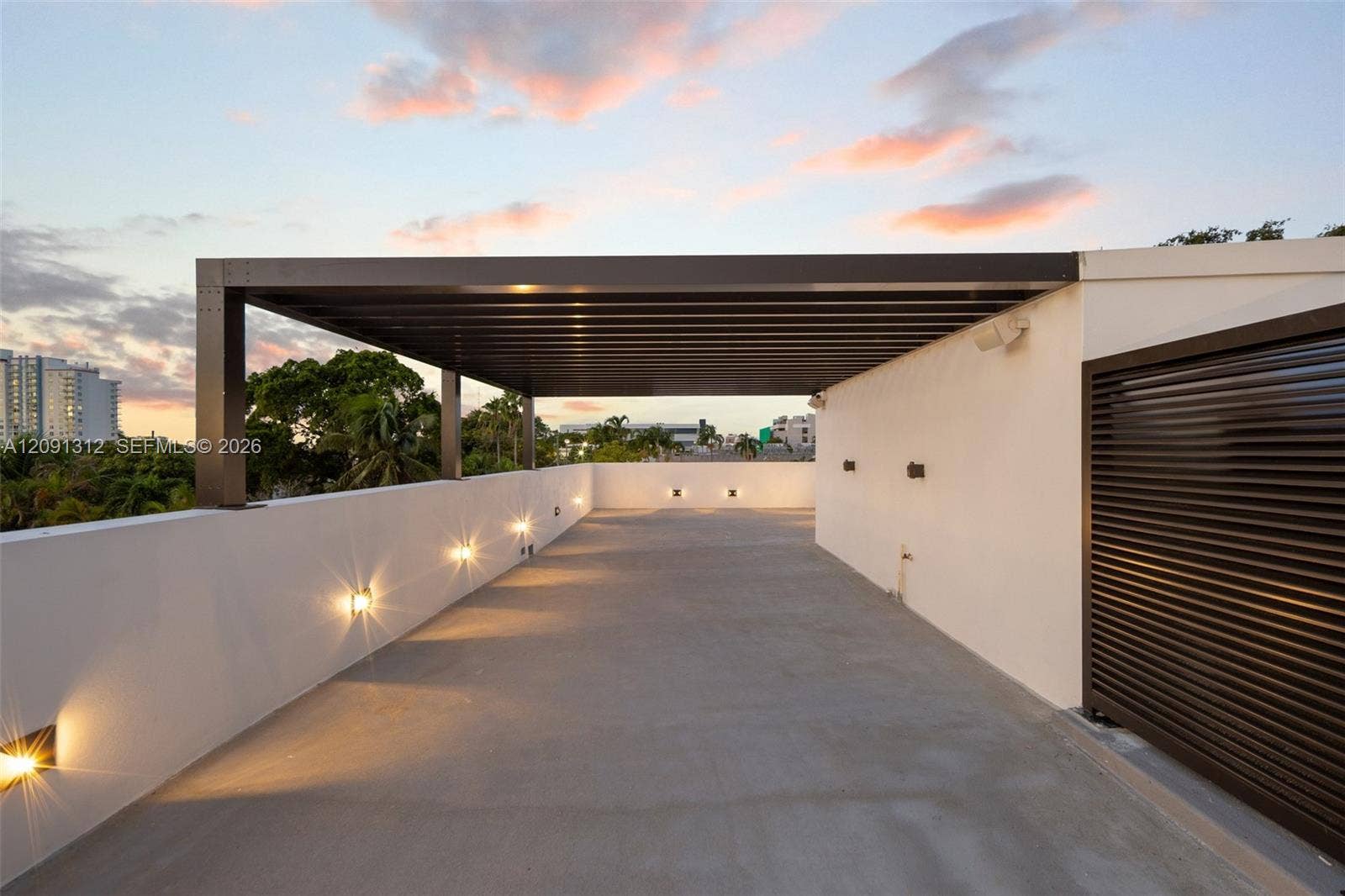 Rooftop terrace featuring a covered pergola, concrete flooring, smooth stucco parapet walls, and integrated wall-mounted lighting