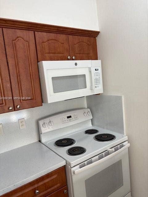 18356 NW 68th Avenue, #E, Hialeah, Hialeah, FL 33015 Kitchen featuring raised-panel wood cabinetry with crown molding, white electric range, and over-the-range microwave