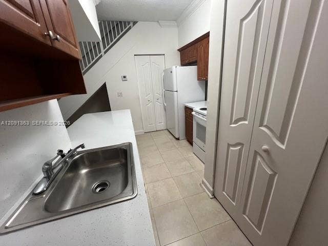 18356 NW 68th Avenue, #E, Hialeah, Hialeah, FL 33015 Kitchen featuring stone-finish countertops, stainless steel sink with metal faucet, wood-toned cabinetry, tile flooring, and bi-fold closet doors