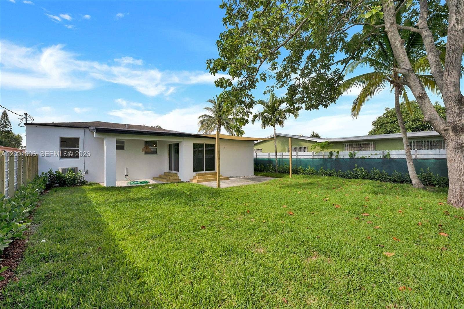 Backyard featuring a concrete patio, wood-finish steps, privacy fencing, and mature trees