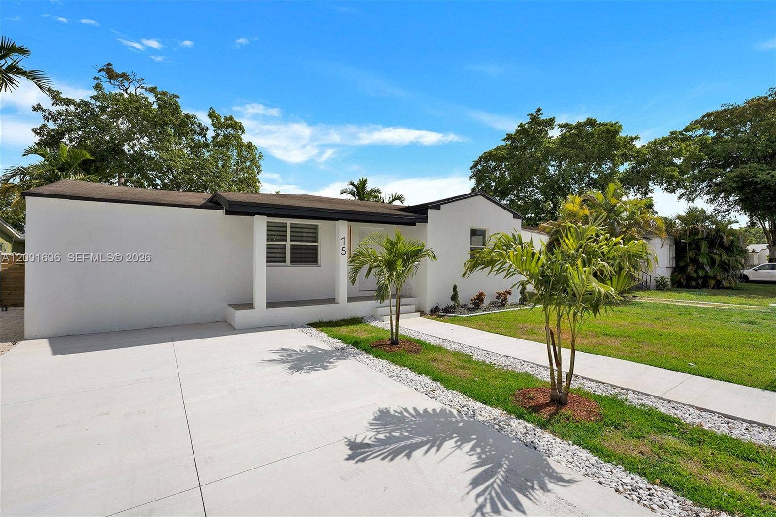 Single-story exterior featuring white stucco finish, flat roofline, concrete driveway, and covered front porch