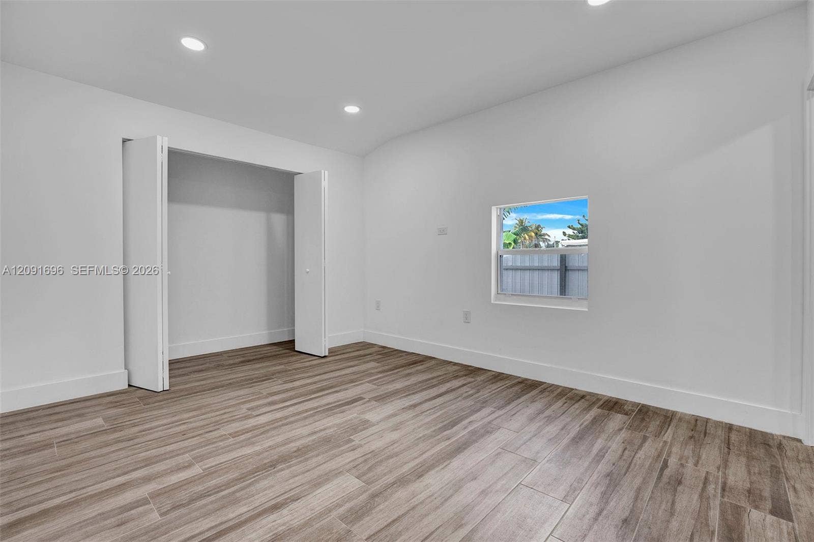 Room featuring wood-finish flooring, recessed lighting, and a closet with bifold doors