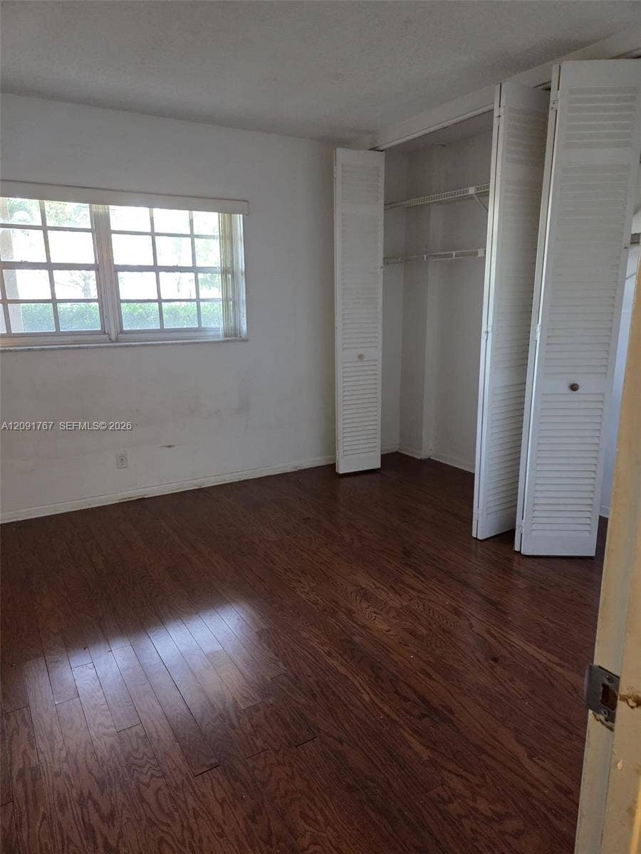 9101 W Sample Road, #102, Coral Springs, FL 33065 Wood-finish flooring, multi-pane window, and closet featuring white louvered bi-fold doors with built-in wire shelving