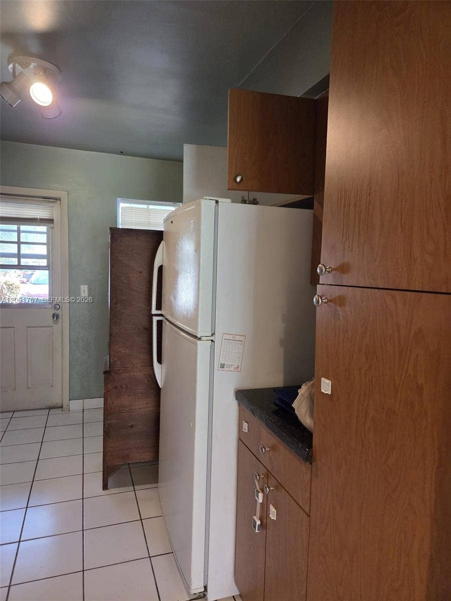 9101 W Sample Road, #102, Coral Springs, FL 33065 Wood-finish cabinetry, floor-to-ceiling pantry storage, ceramic tile flooring, and multi-light ceiling fixture
