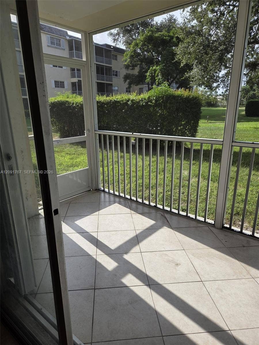 9101 W Sample Road, #102, Coral Springs, FL 33065 Screened-in porch featuring tile flooring, metal frame enclosures, and a metal railing