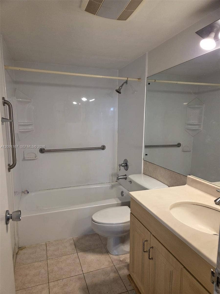 9101 W Sample Road, #102, Coral Springs, FL 33065 Full-width vanity with integrated countertop and sink, large wall-mounted mirror, tub-shower combination with surround, and ceramic tile flooring