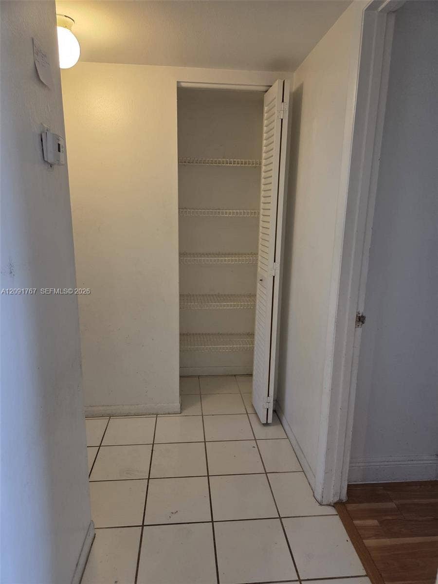 9101 W Sample Road, #102, Coral Springs, FL 33065 Storage closet featuring louvered bi-fold doors, white wire shelving, and tiled flooring