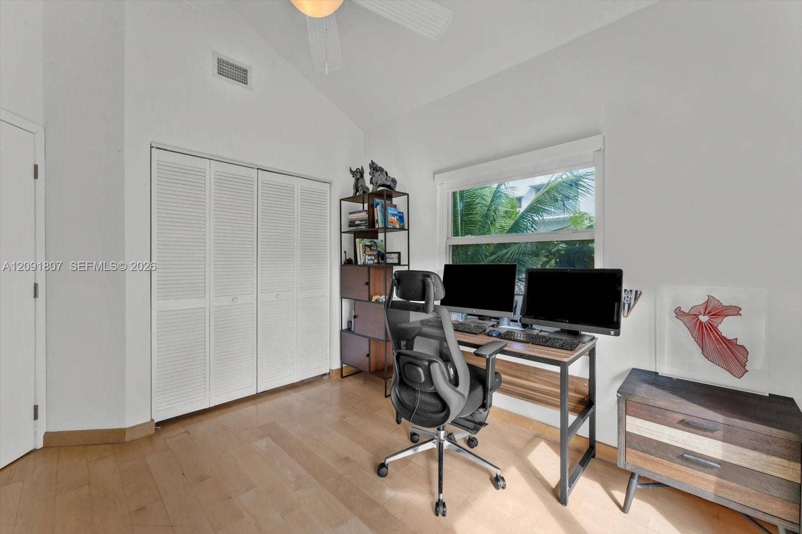 Vaulted ceilings, wood-finish flooring, and white louvered-door closet featuring a ceiling fan and natural lighting