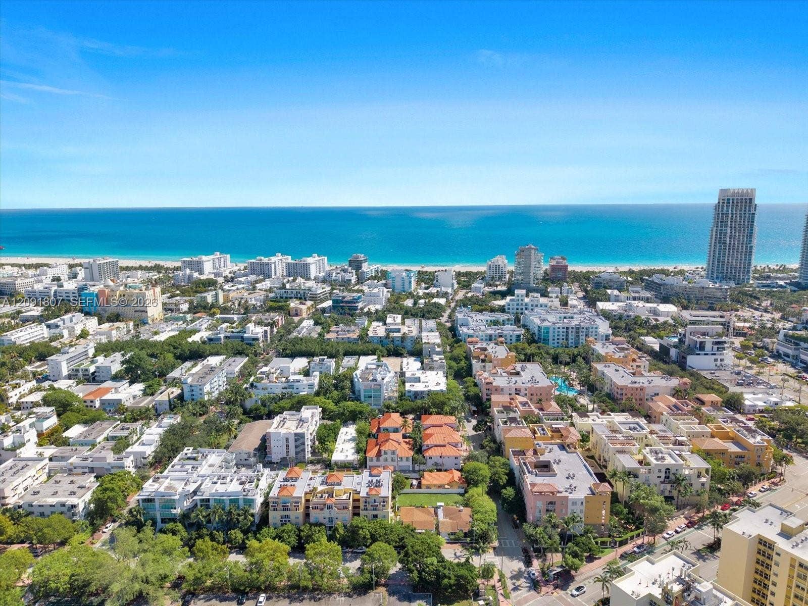 Aerial perspective featuring an expanse of mature tropical vegetation, proximity to coastal shoreline, and high-density urban development
