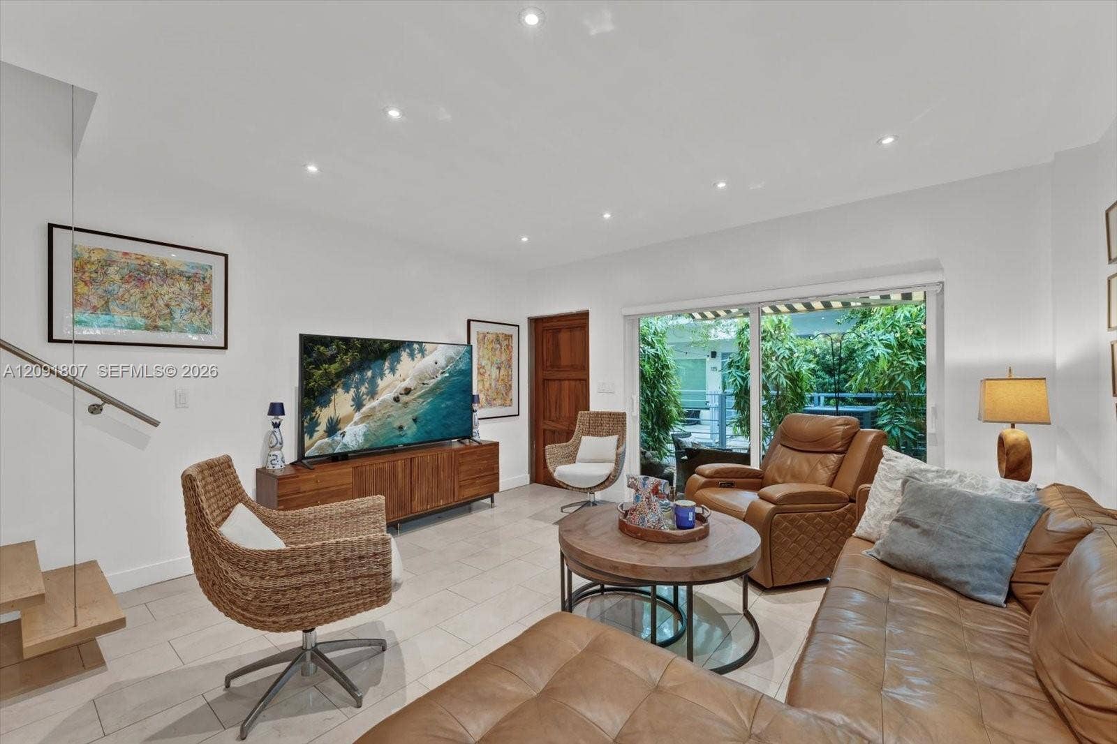 Large-format tile flooring, recessed ceiling lighting, sliding glass door with exterior access, and a floating wood-tread staircase with a glass panel railing