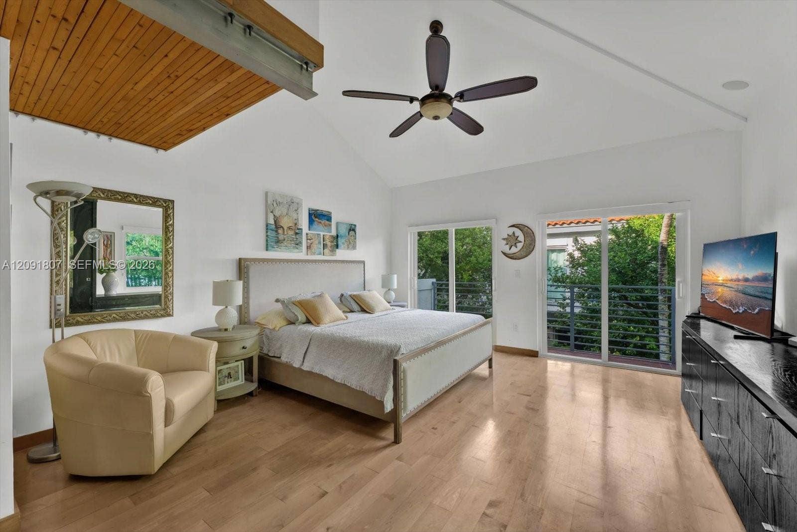 Vaulted ceilings with wood-plank detailing, wood-finish flooring, and sliding glass doors with balcony access