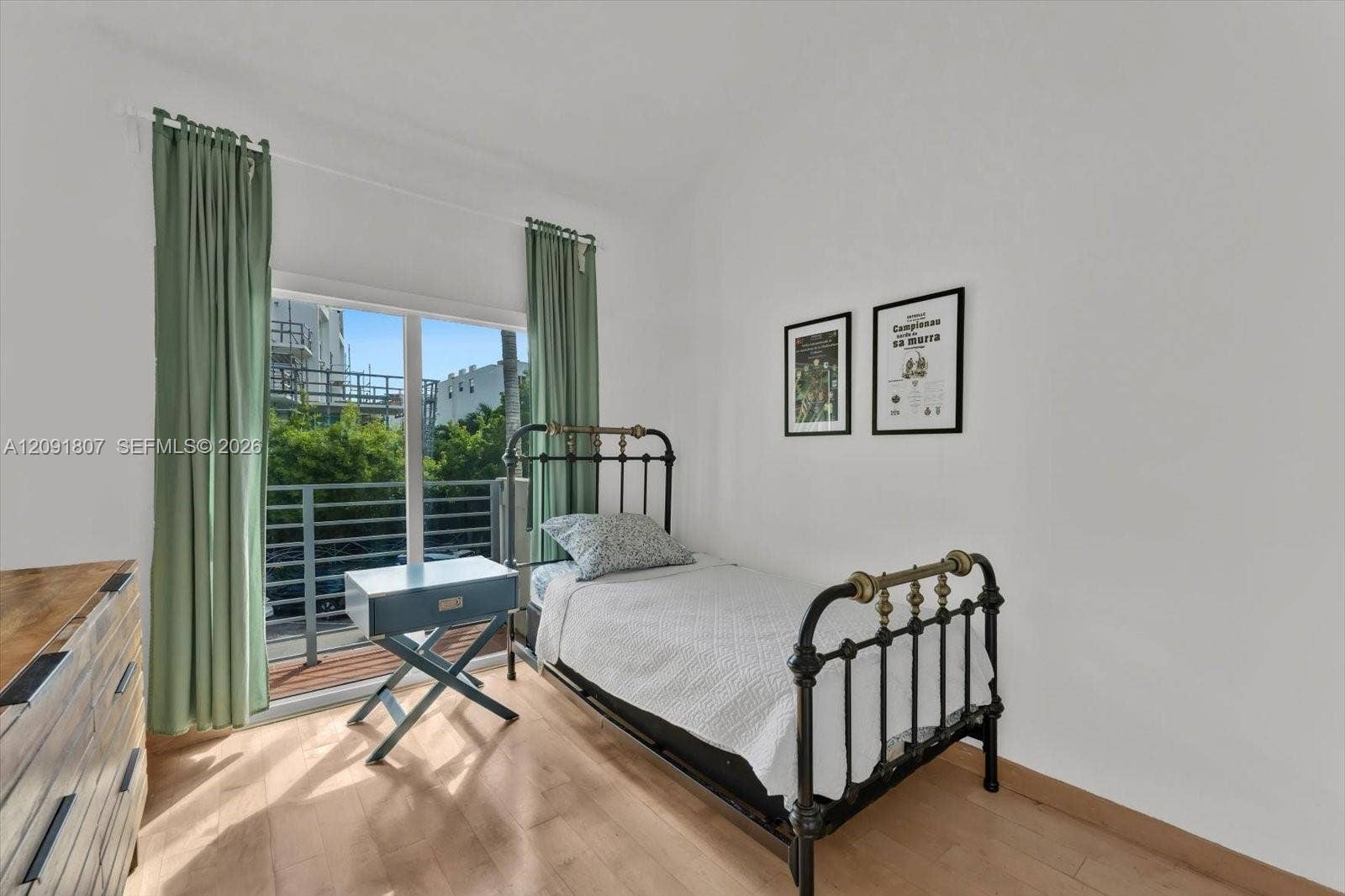 Sliding glass door opening to a private balcony with metal railing, paired with wood-finish flooring