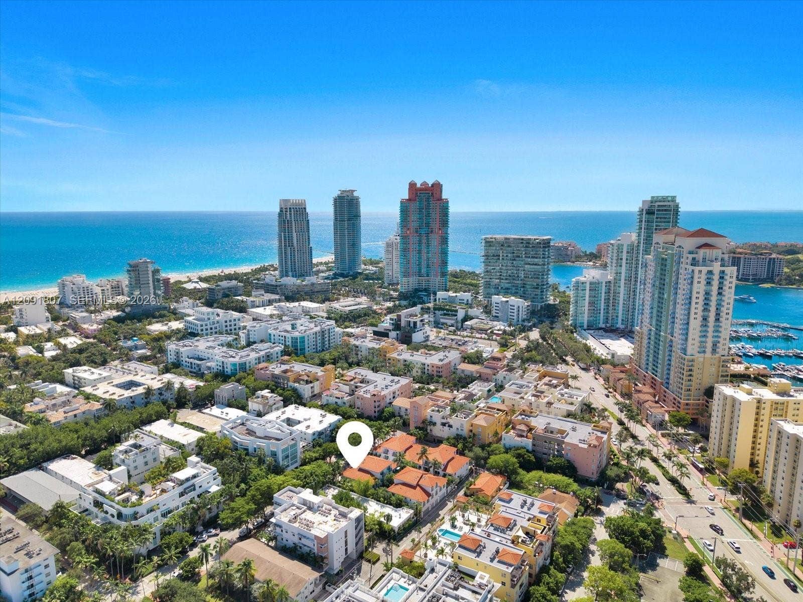 Aerial perspective featuring a low-rise residential complex with terracotta-style roofing, situated within a dense urban landscape featuring proximity to the coastline and high-rise developments