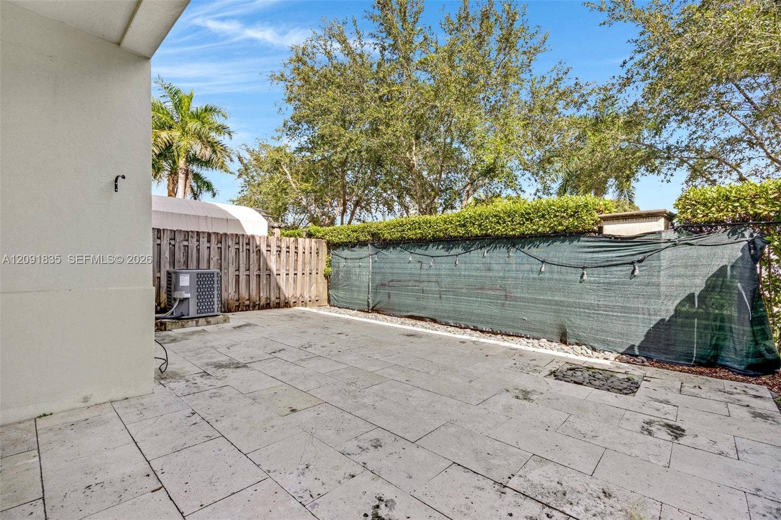 22409 SW 102nd Avenue, Miami, FL 33190 Concrete paver patio with a smooth-finish exterior wall, privacy fencing, and mature trees