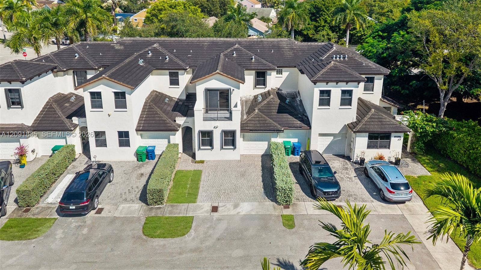 22409 SW 102nd Avenue, Miami, FL 33190 Multi-unit structure featuring a light-toned stucco exterior, dark shingle roof, paved private driveways, and upper-level balconies