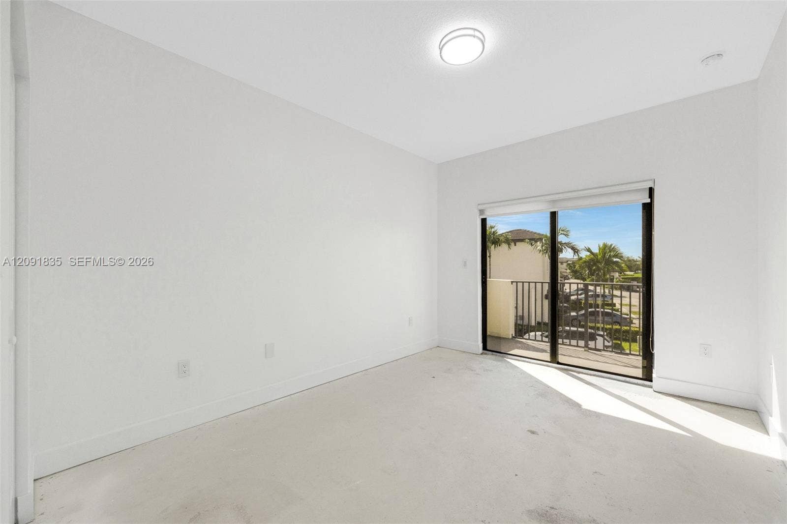 22409 SW 102nd Avenue, Miami, FL 33190 Interior space featuring neutral wall paint, flush-mount ceiling lighting, and sliding glass doors opening to a balcony with metal railings