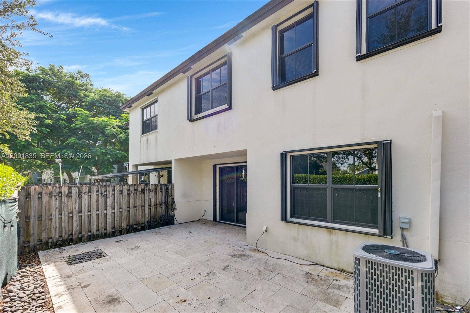 22409 SW 102nd Avenue, Miami, FL 33190 Stucco exterior featuring a paved stone patio, sliding glass doors, and a wood privacy fence