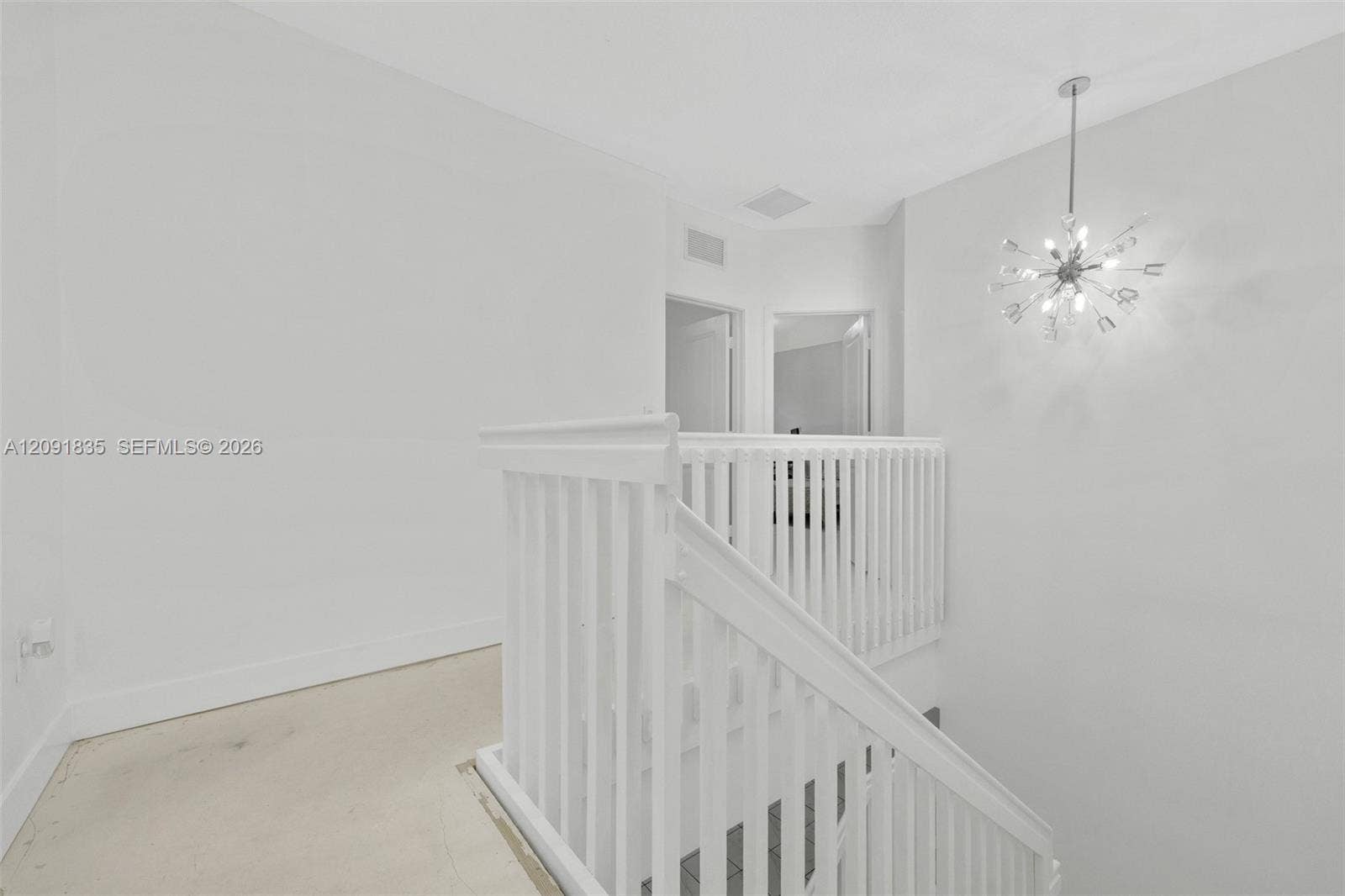 22409 SW 102nd Avenue, Miami, FL 33190 White stairwell featuring a wood handrail, vertical balusters, and a starburst chandelier