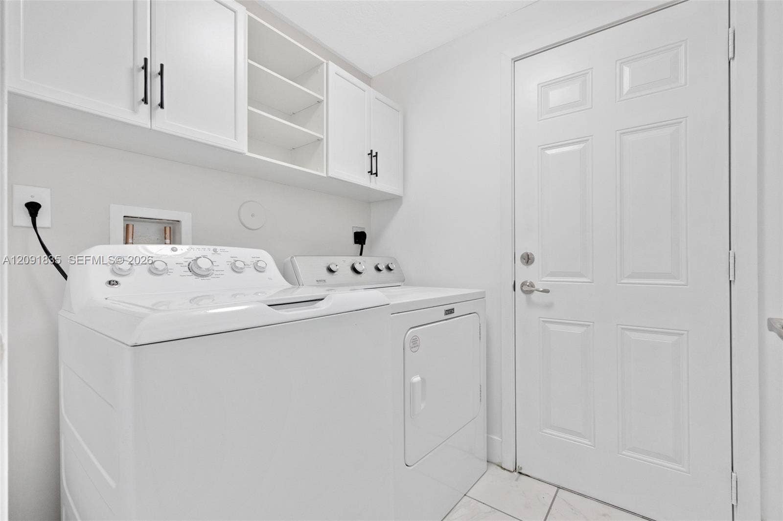 22409 SW 102nd Avenue, Miami, FL 33190 Laundry area featuring white shaker-style wall cabinets with matte black hardware, open shelving, and tile flooring
