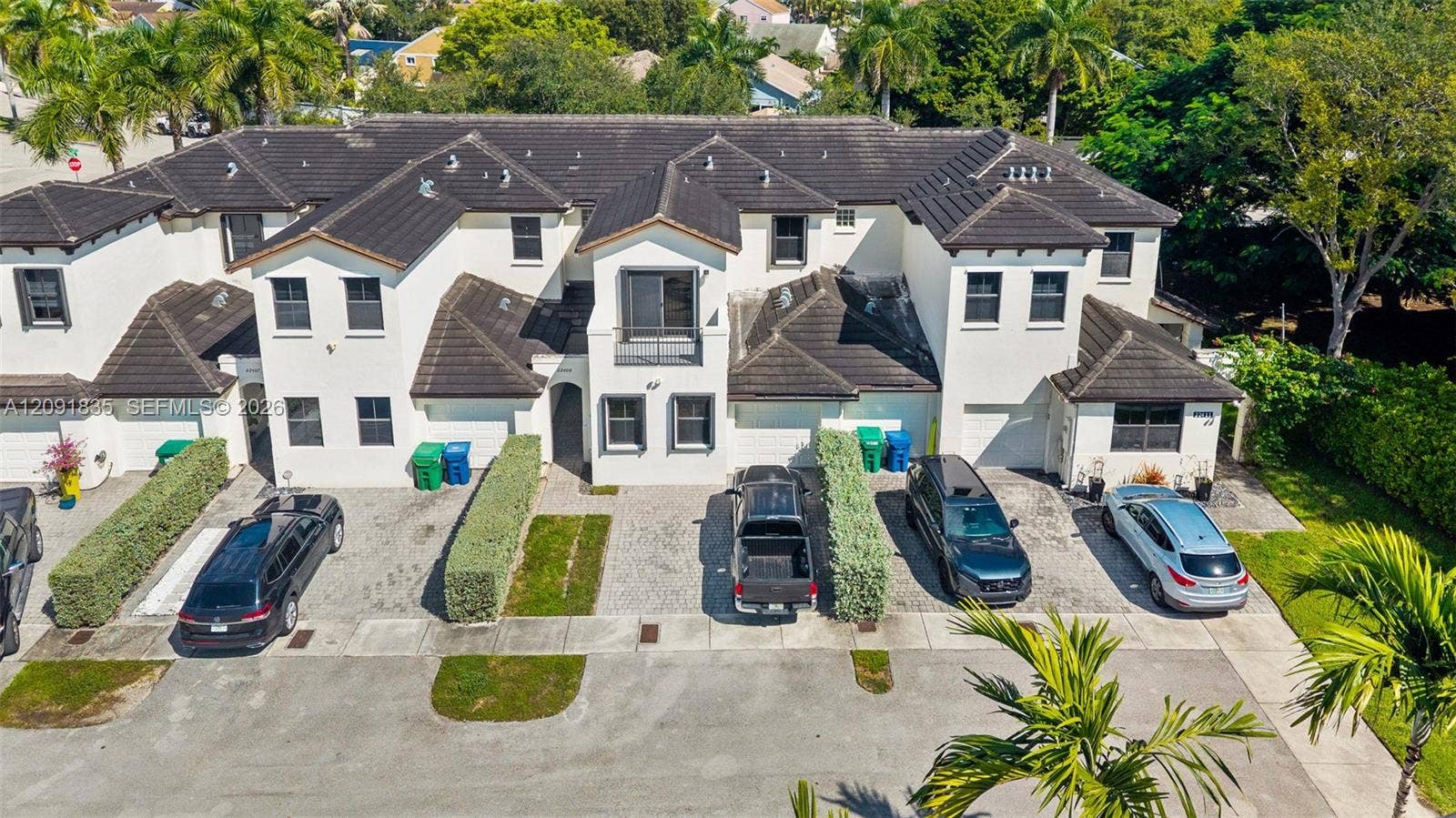 22409 SW 102nd Avenue, Miami, FL 33190 Multi-unit residential structure with stucco exterior, dark tile roofing, individual attached garages, and private balconies