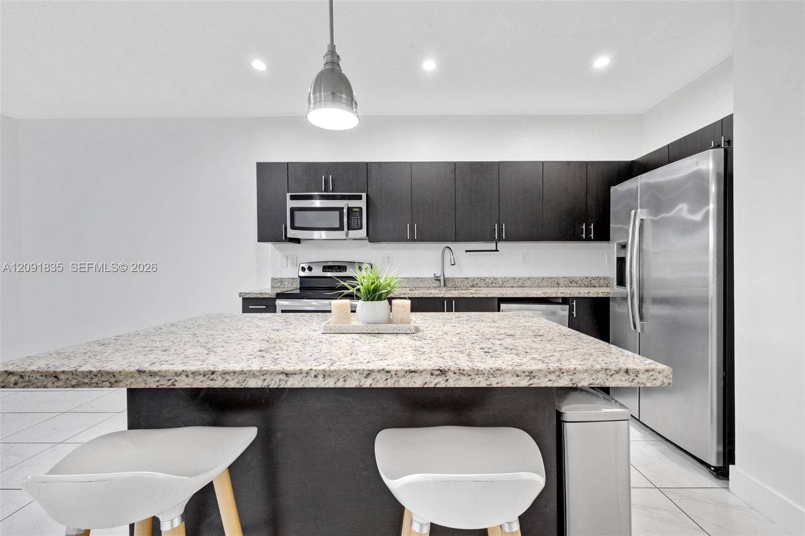 22409 SW 102nd Avenue, Miami, FL 33190 Kitchen featuring dark-toned cabinetry, light-toned stone-finish island countertop, stainless steel appliances, recessed ceiling lighting, and tile flooring