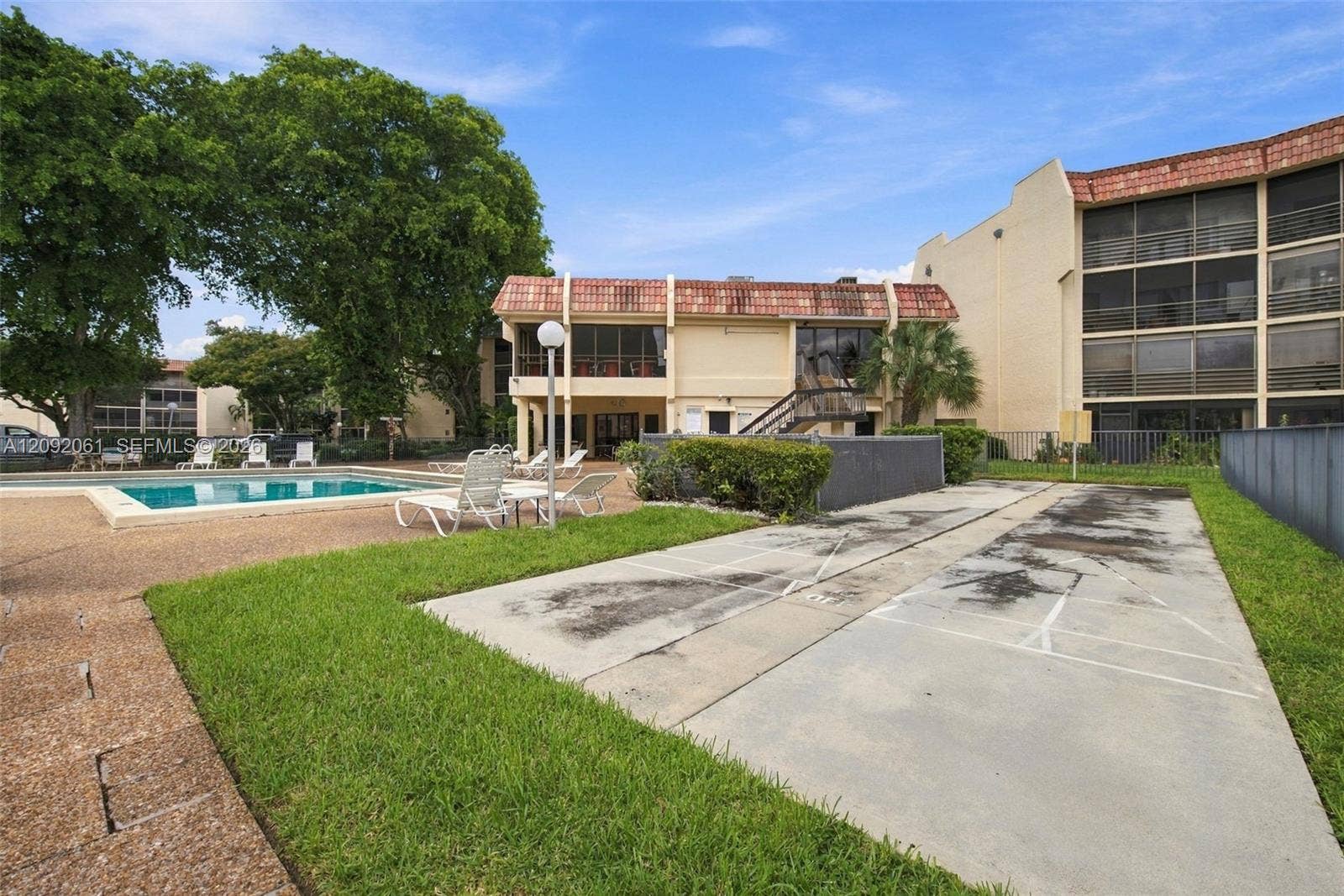 6555 W Broward Boulevard, #309, Plantation, FL 33317 Outdoor recreational area featuring a swimming pool, shuffleboard court, manicured lawn, and mature landscaping
