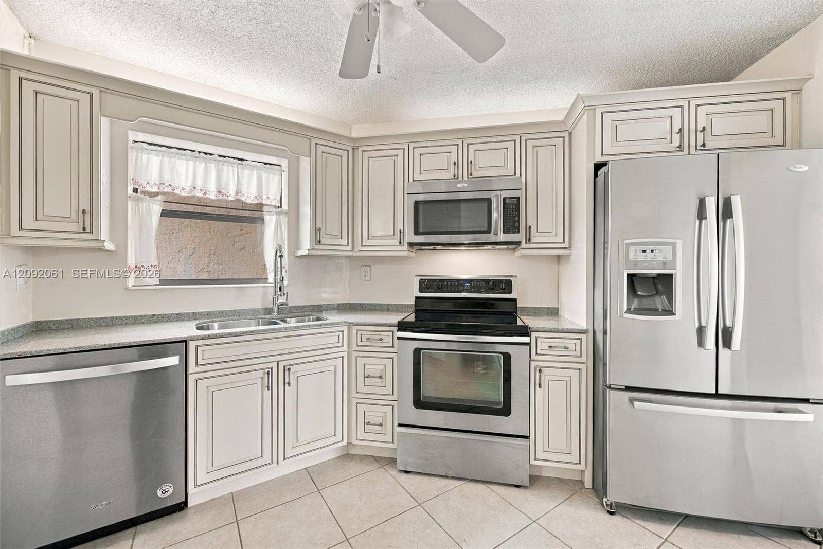 6555 W Broward Boulevard, #309, Plantation, FL 33317 Kitchen featuring light-toned cabinetry, stainless steel appliances, speckled stone-finish countertops, and tile flooring