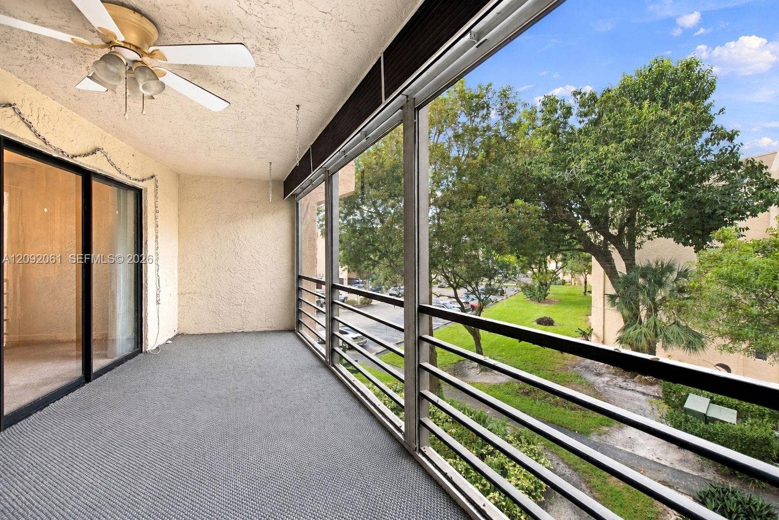 6555 W Broward Boulevard, #309, Plantation, FL 33317 Covered balcony with screened enclosure, metal railing, ceiling-mounted fan with light fixture, and sliding glass door