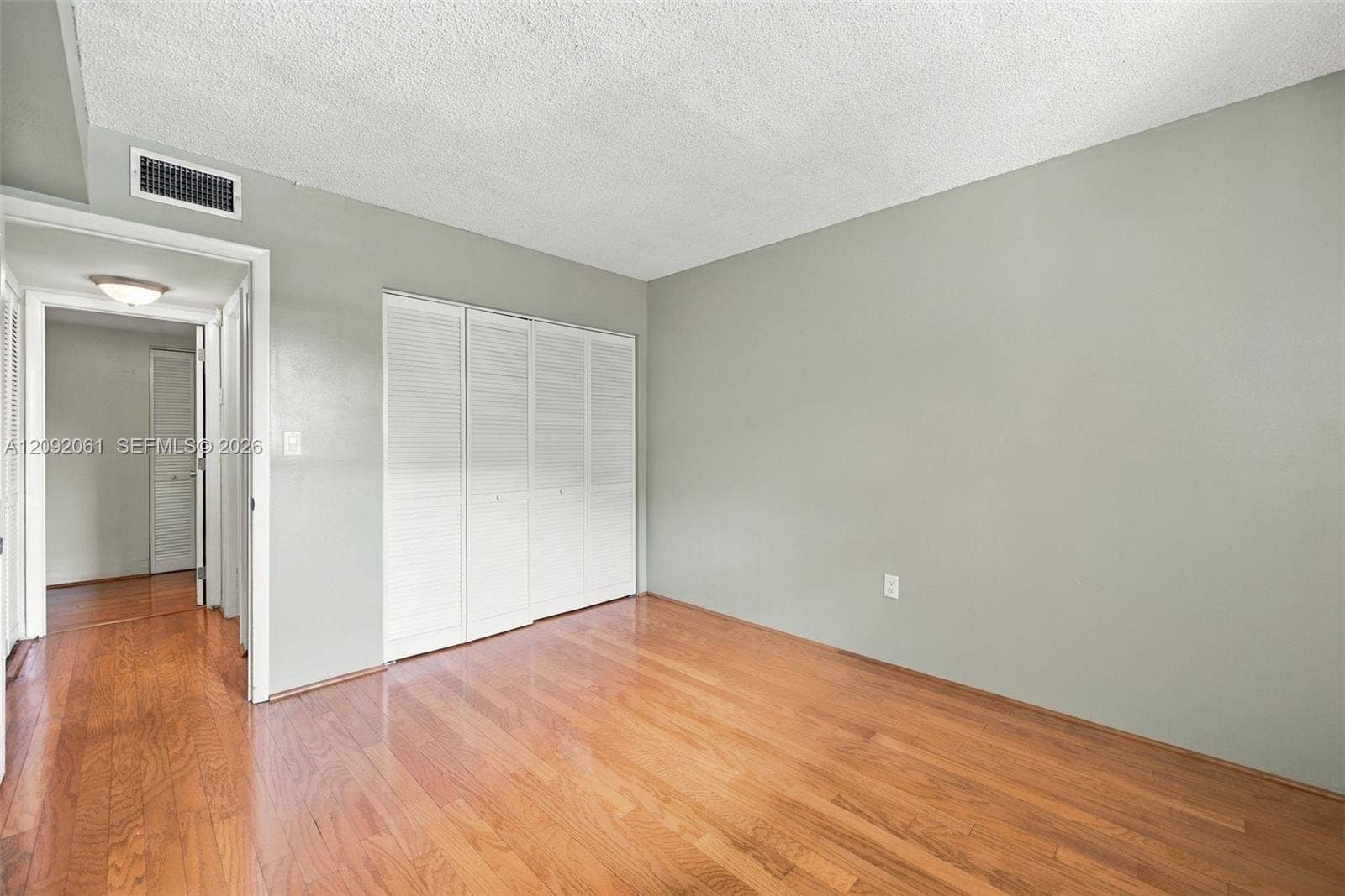 6555 W Broward Boulevard, #309, Plantation, FL 33317 Room interior featuring wood-finish flooring, neutral-toned walls, and a multi-panel louvered closet door