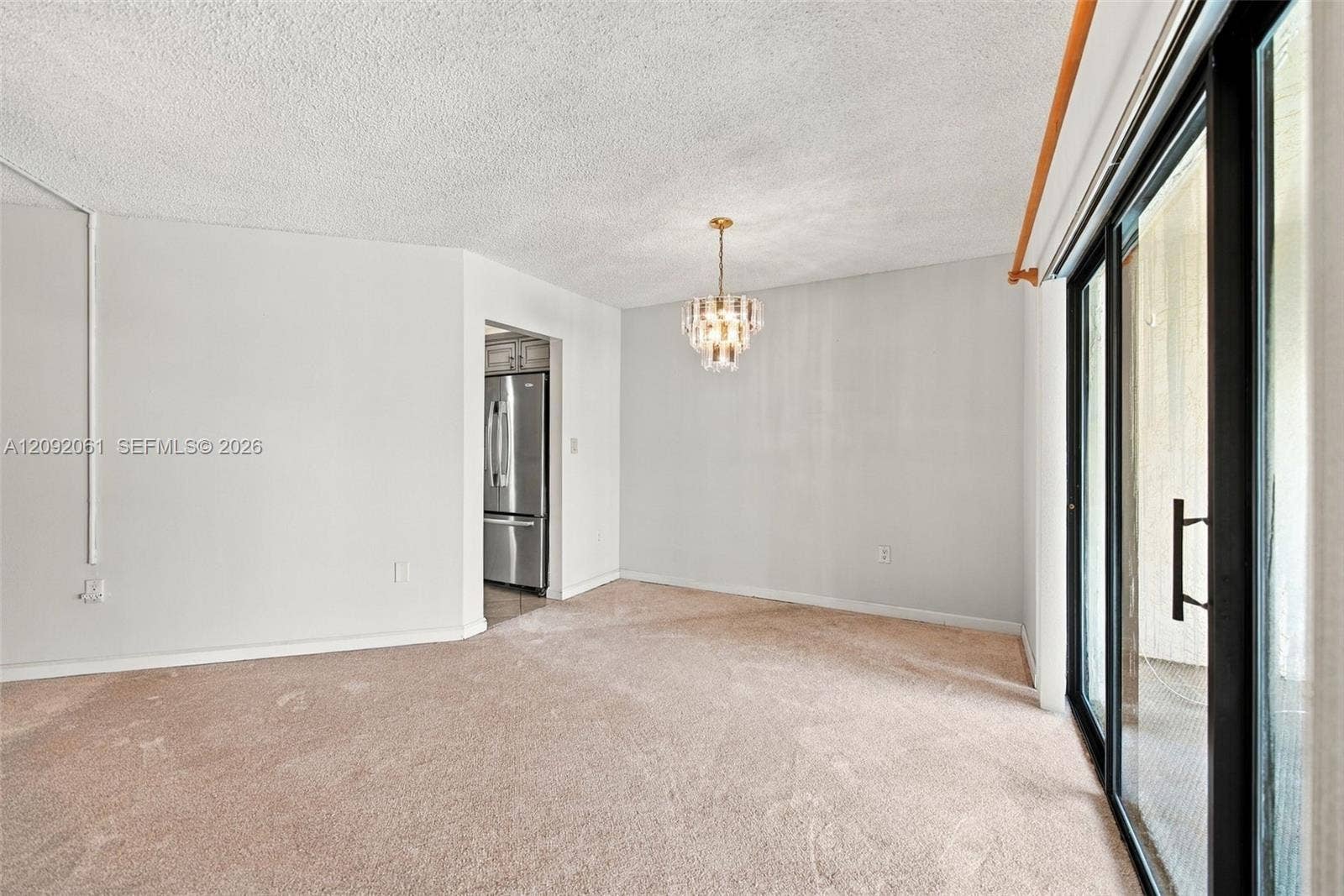 6555 W Broward Boulevard, #309, Plantation, FL 33317 Multi-tiered crystal chandelier, wall-to-wall carpeting, sliding glass doors with black frames, and stainless steel kitchen appliances