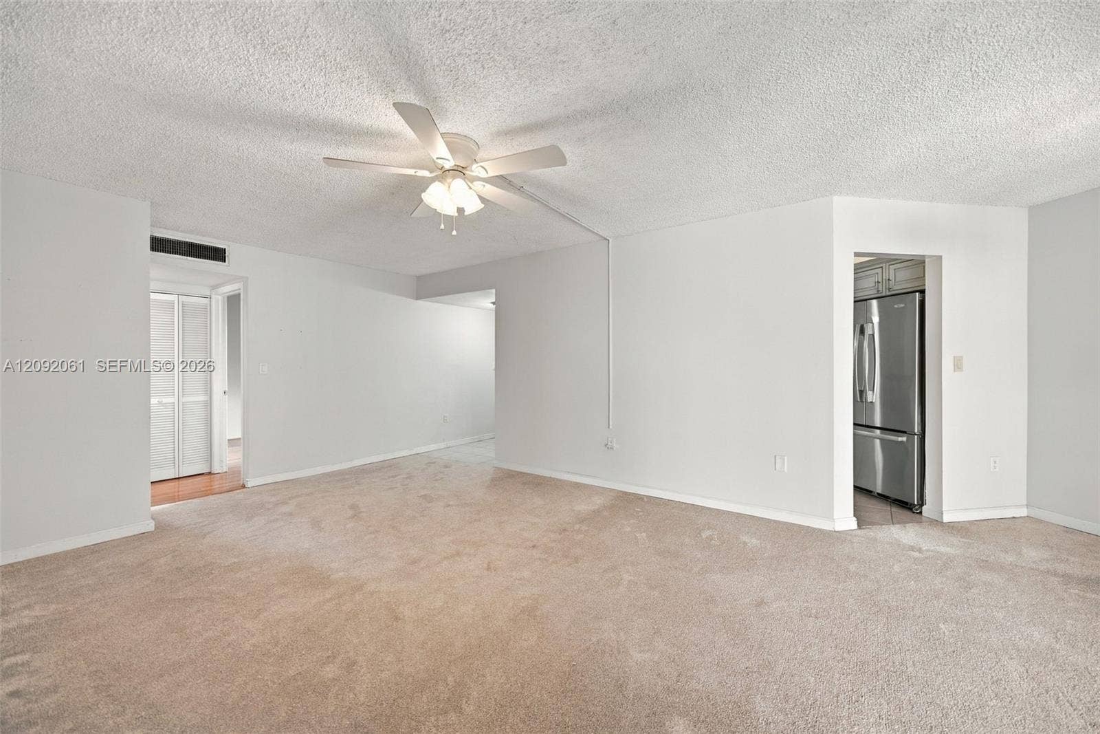6555 W Broward Boulevard, #309, Plantation, FL 33317 Neutral wall palette with carpeted flooring, featuring a ceiling-mounted light fixture with fan and built-in stainless steel refrigerator