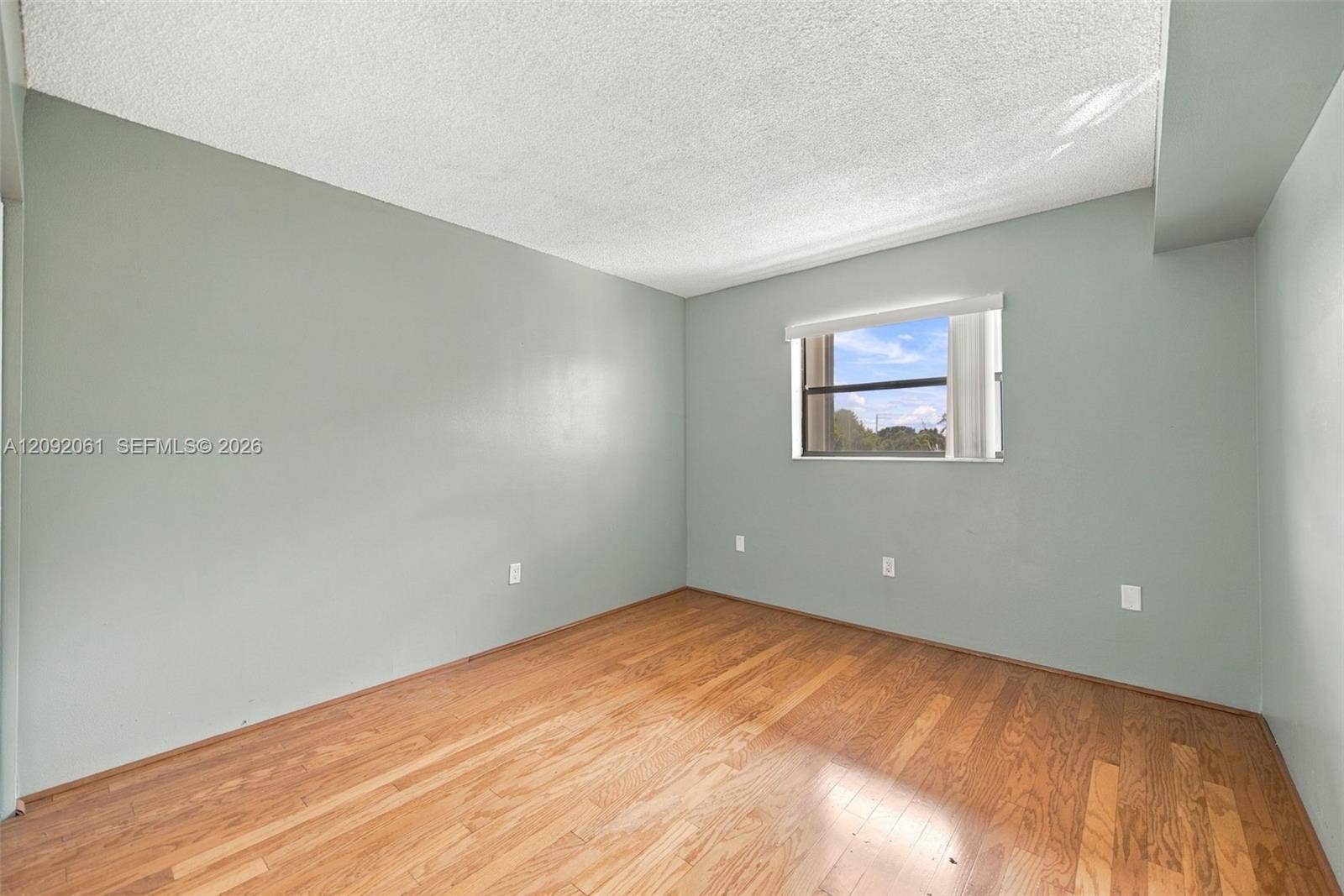 6555 W Broward Boulevard, #309, Plantation, FL 33317 Interior room featuring wood-finish flooring, light-toned wall paint, and a single-pane window with a horizontal blind